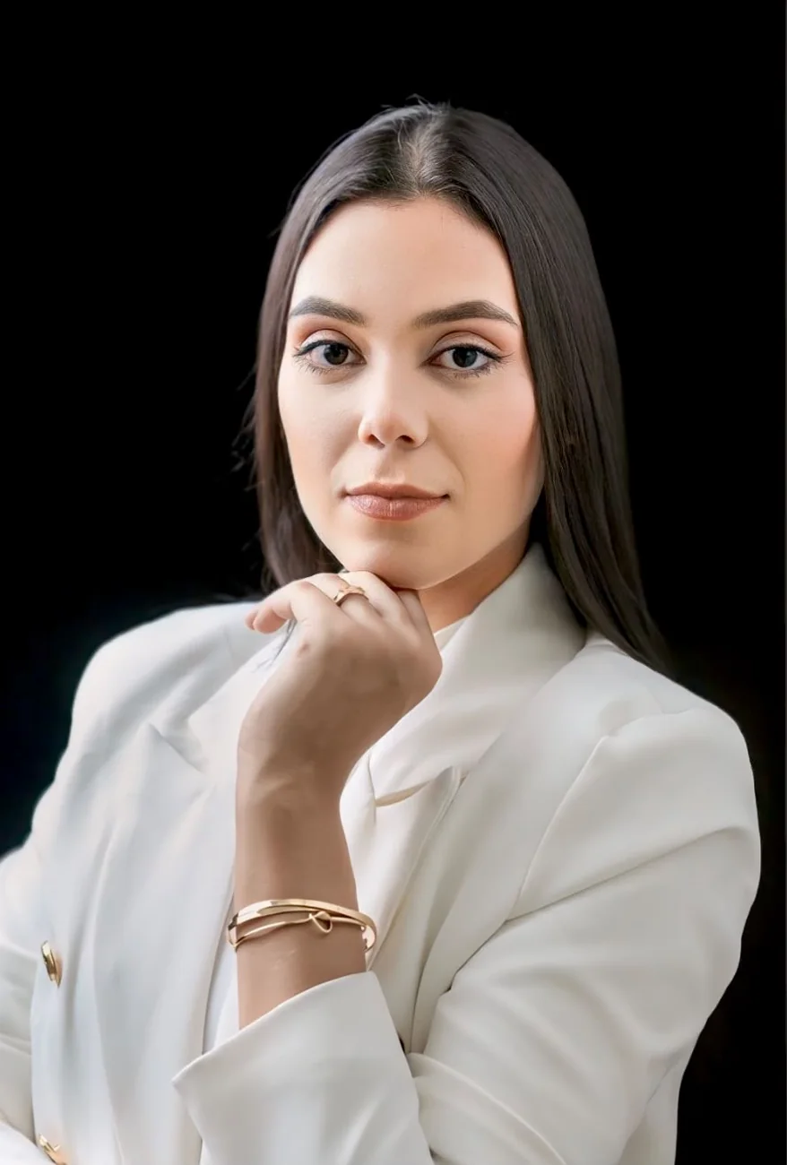 Retrato da advogada Laiys Alves com blazer branco e a mão apoiada no queixo